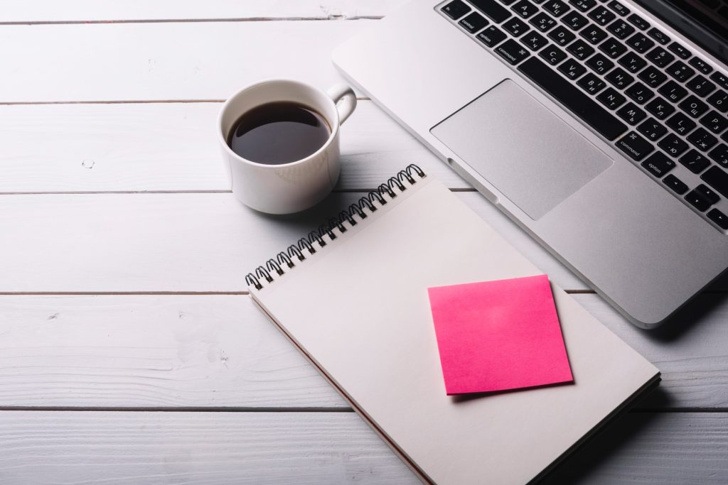 Laptop és füzet íróasztalon – egyedi Kajabi és WordPress fejlesztési projektek